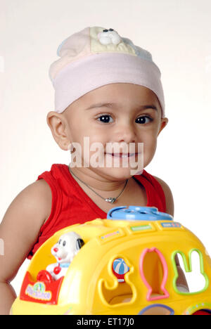 Indian baby boy white cap red dress playing with yellow ball India MR#152 Stock Photo