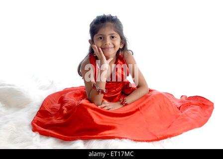 Indian baby girl child sitting hand on face red dress white background - MR#736M - rmm 151197 Stock Photo