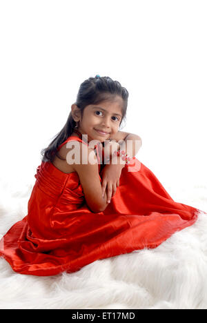 Girl wearing red dress sitting on white background and looking at camera MR#736M Stock Photo