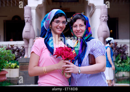 Women mother and daughter exchanging flowers celebrating Parsi New Year in Fire Temple Mumbai India - MR#784L & 364 - RMM 179732 Stock Photo