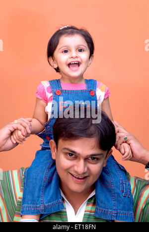 Baby daughter sitting on shoulder of man father holding hands India - MR#364 Stock Photo
