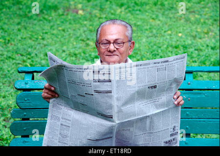 Old man reading newspaper on garden bench - MR#364 Stock Photo