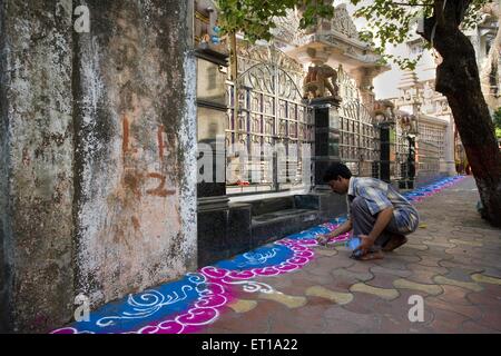 Man doing rangoli colorful floor decoration outside Jain temple for festival, Bombay, Mumbai, Maharashtra, India, Asia, Asian, Indian Stock Photo