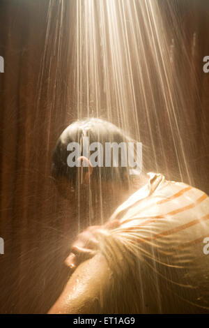 Man bathing under shower water Bathroom flow bathing in light ; Palolem beach ; Goa ; India Stock Photo