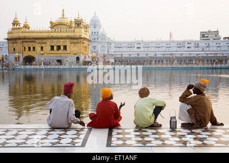 Sikh Devotees sitting evening holy water of the pool near ; Hari Mandir Sahib Swarn Mandir Golden temple ; Amritsar Stock Photo