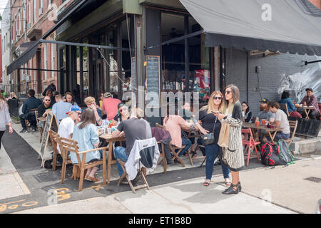 Outdoor dining in Bushwick, Brooklyn in New York during the annual Bushwick Collective Block Party on Saturday, June 6, 2015. Music and partying brought some but the real attraction was the new murals  by 'graffiti' artists that decorate the walls of the buildings that the collective uses.  (© Richard B. Levine) Stock Photo