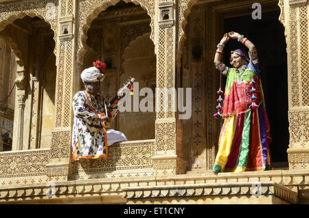 Folk musicians One man playing musical instrument and woman dancing inside fort Jaisalmer Rajasthan India Stock Photo