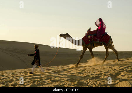 Man Dragging Camel with Woman Sitting on it  Sand Dune Jaisalmer Rajasthan India Asia MR # 704 Stock Photo