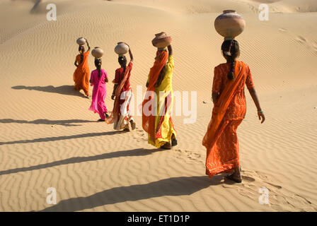 Five Indian women with earthen pots balancing on head walking in Thar desert , Khuhri , Jaisalmer , Rajasthan , India , Asia