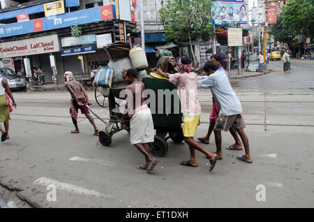 Labourers dragging road repairing machine on street in Kolkata at West Bengal India Asia Stock Photo