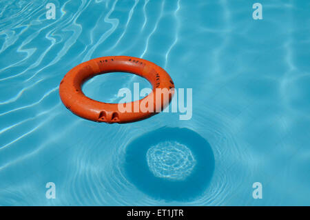 Lifeguard ring floating on blue water in swimming pool Stock Photo