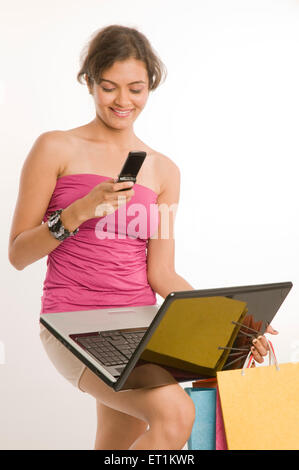 Girl standing with laptop and using mobile phone Pune Maharashtra India Asia MR#686 M June 2011 Stock Photo