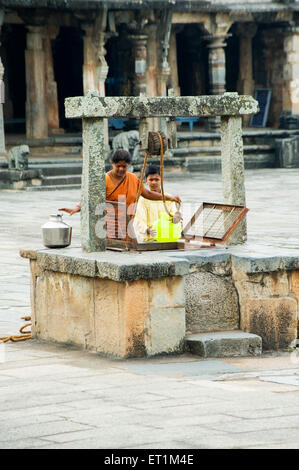 South Indian woman with boy drawing water from well ; Karnataka ; India NOMR Stock Photo