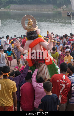 big heavy idol of Lord Ganesh being lifted and carried for immersion Pune Maharashtra India Stock Photo