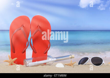 Beach scene with flip flops sandals and bottle post in summer vacation, holidays Stock Photo