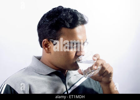 Young man drinking water from glass ; India MR#556 Stock Photo