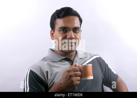 Young man drinking tea or coffee from mug ; India MR#556 Stock Photo