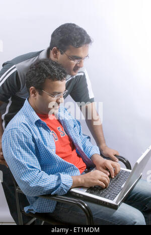 Two young men working on laptop ; India MR#556 Stock Photo