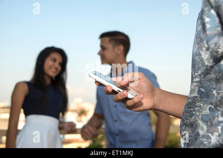 Teenagers checking mobile phone together outdoors Stock Photo