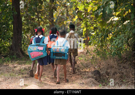 Students children boys girls walking to village school carrying heavy school bag in Maharashtra India Asia Stock Photo