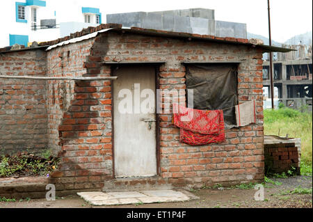 exposed brick wall house closed door plastic window laundry drying India Stock Photo