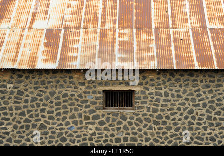 Stone wall with window and rusted metal roof ; Akluj ; Solapur ; Maharashtra ; India Stock Photo