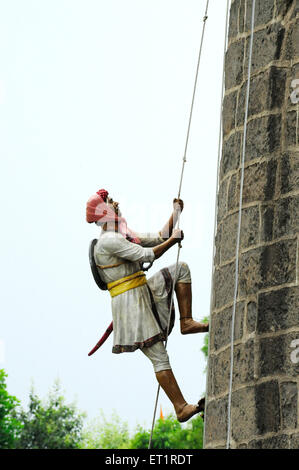 Maratha soldier trying to climb fort wall holding rope at akluj fort ; Solapur ; Maharashtra ; India Stock Photo