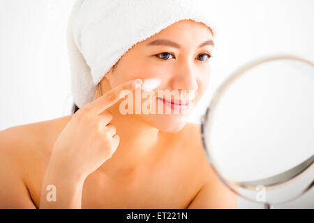 smiling woman applying cream lotion on face Stock Photo