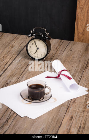 Old clock, hat, coffee and paper sheets on old Wooden table. Stock Photo