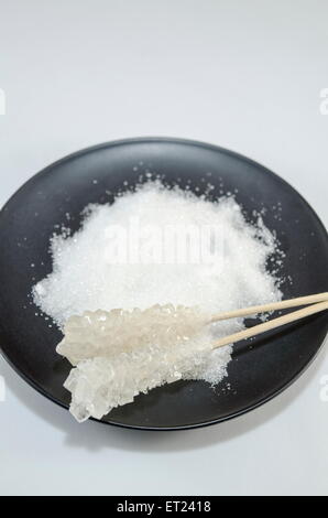 Two sugar sticks containing white and brown sugar in a black plate Stock Photo