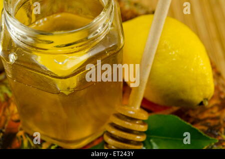 Jar of honey a wooden spoon and lemon on a table Stock Photo