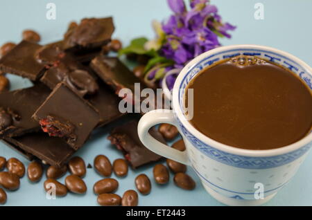 Dark chocolate with raisins, chocolate balls and a cup of coffee on a blue surface Stock Photo