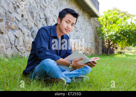 Young boy reading book in the park outdoor Stock Photo