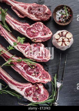 Raw lamb chops with garlic and herbs on the old wooden table. Stock Photo