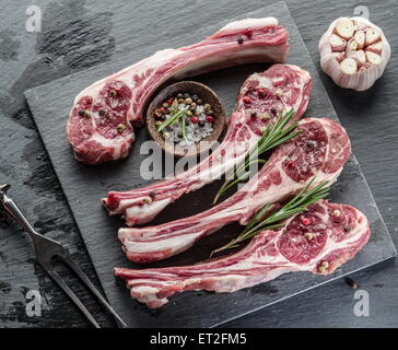 Raw lamb chops with garlic and herbs on the old wooden table. Stock Photo