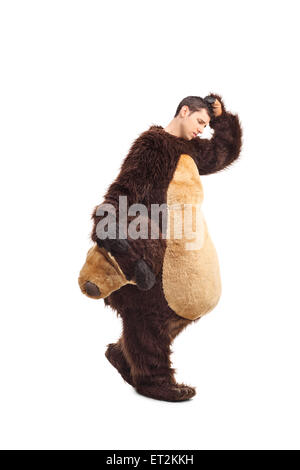 Full length portrait of a sad young man in a bear costume walking and scratching his head isolated on white background Stock Photo