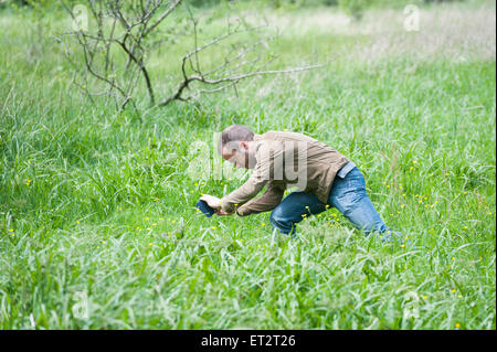 A man taking a photograph using a mobile phone camera in the countryside UK Stock Photo