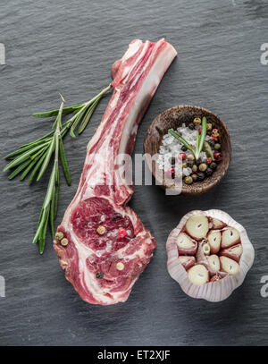 Raw lamb chops with garlic and herbs on the old wooden table. Stock Photo