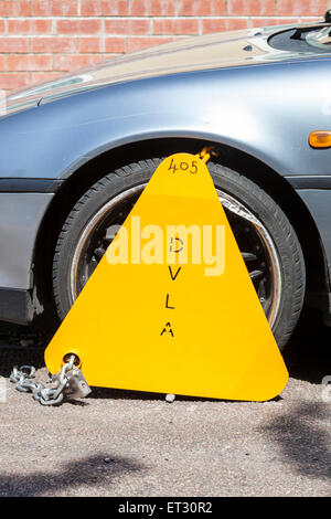 Clamped car wheel. DVLA wheel clamp attached to a car due to unpaid road tax, England, UK Stock Photo