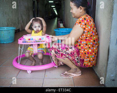 Mahachai, Samut Sakhon, Thailand. 11th June, 2015. A Burmese migrant and her child in the hallway of a tenement building for migrant workers in Mahachai. Labor activists say there are about 200,000 migrant workers from Myanmar (Burma) employed in the fishing and seafood industry in Mahachai, a fishing port about an hour southwest of Bangkok. Since 2014, Thailand has been a Tier 3 country on the US Department of State Trafficking in Persons Report (TIPS). Tier 3 is the worst ranking, being a Tier 3 country on the list can lead to sanctions. Tier 3 countries are ''Countries whose governments do Stock Photo