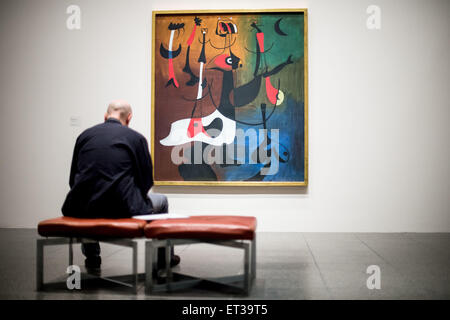 Duesseldorf, Germany. 11th June, 2015. A visitor sits in front of the painting 'Rhythmic Figures' (1934, oil on canvas) by the Catalan painter Miro (1893-1983) before a press conference in the Kunstsammlung Nordrhein-Westfalen in Duesseldorf, Germany, 11 June 2015. The exhibition 'Miro. Painting as Poetry.' - which includes around 110 pieces from all periods of the artist's work - can be seen from 13 June to 27 September 2015 in K20. Photo: MAJA HITIJ/dpa/Alamy Live News Stock Photo