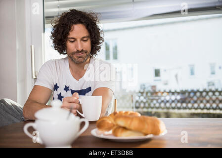 Mid adult man drinking cup of coffee at breakfast table, Munich, Bavaria, Germany