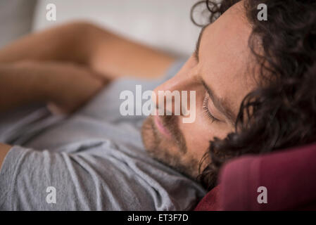 Mid adult man sleeping on couch, Munich, Bavaria, Germany Stock Photo