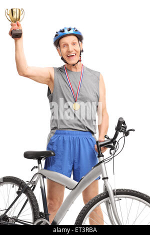 Vertical shot of an overjoyed senior cyclist holding a golden trophy and looking at the camera isolated on white background Stock Photo