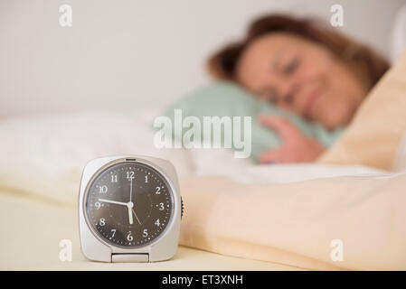 Woman asleep in bed while her alarm shows the early time at home in bedroom, Munich, Bavaria, Germany Stock Photo