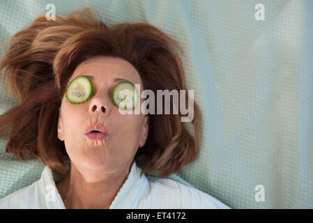 Senior woman with cucumber slices on her eyes, Munich, Bavaria, Germany Stock Photo