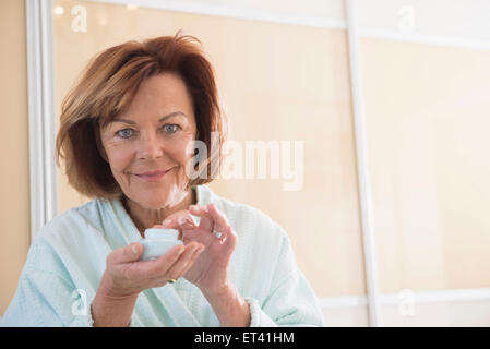 Senior woman applying moisturizer on her face, Munich, Bavaria, Germany Stock Photo