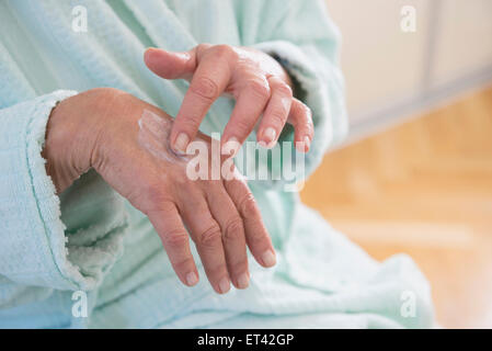 Senior woman applying moisturizer on her hand, Munich, Bavaria, Germany Stock Photo