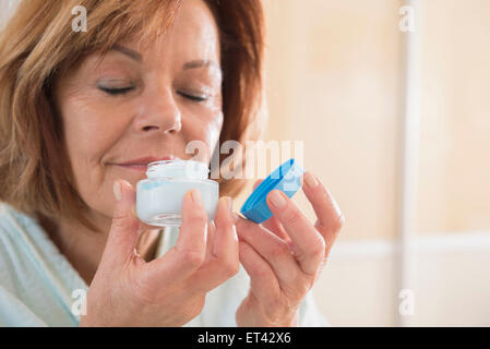 Senior woman smelling sun cream, Munich, Bavaria, Germany Stock Photo