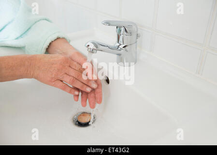 Senior woman washing hands in bathroom sink, Munich, Bavaria, Germany Stock Photo